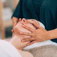 Close-up of a young woman’s face. Client receiving face lifting treatment with prayer hold technique.
