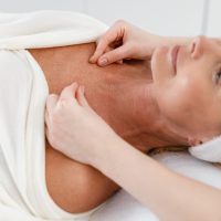Happy adult pretty confident female client getting massage in cosmetologist cabinet, spa procedure