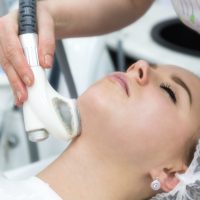 A beautiful blonde smooths wrinkles on the face and neck area with the help of massage in the beauty salon.